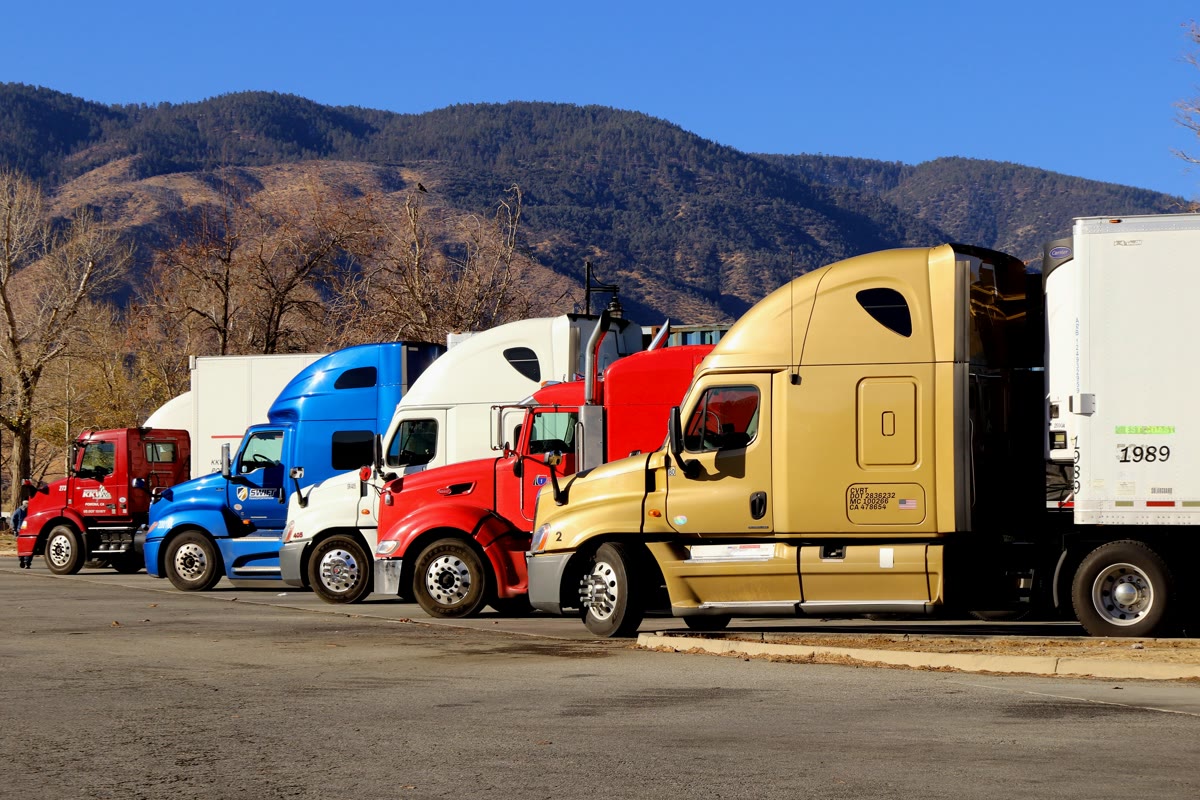 Semi trucks parked at the Lebec rest area on Interstate 5 in California, with mountains behind them